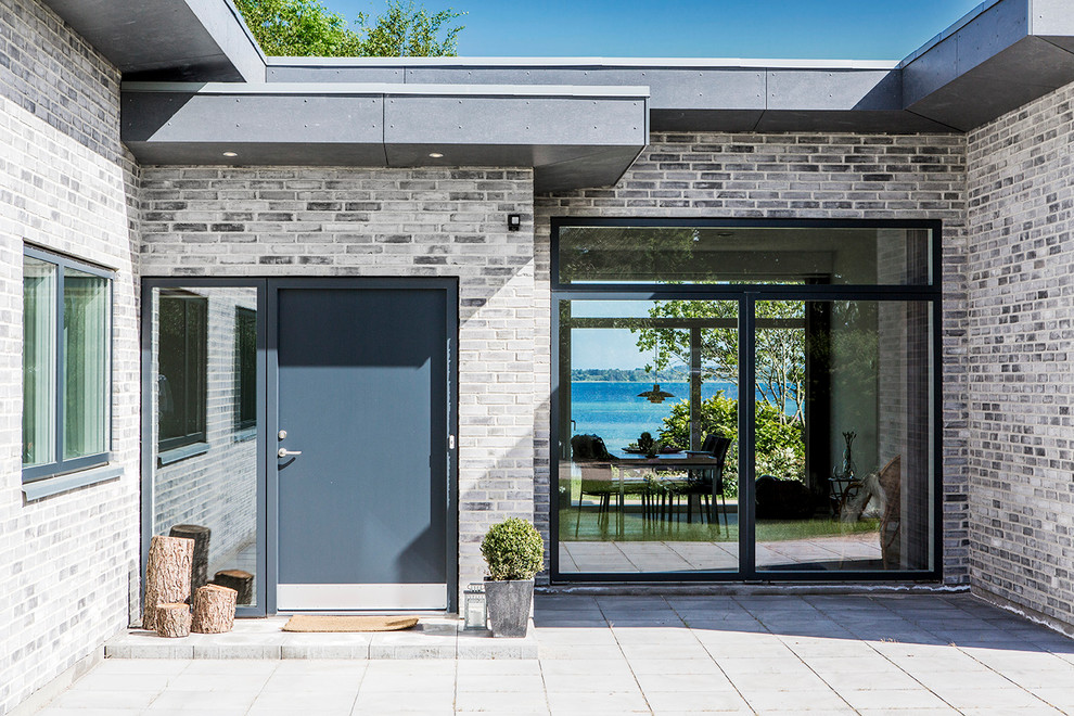 Idéer för att renovera en skandinavisk entré, med grå väggar, en enkeldörr och en svart dörr