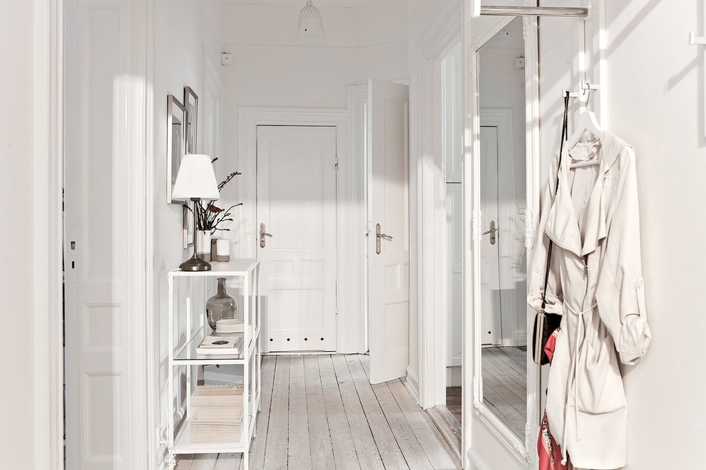 Imagen de hall nórdico con paredes blancas, suelo de madera clara, puerta blanca, suelo blanco y puerta simple