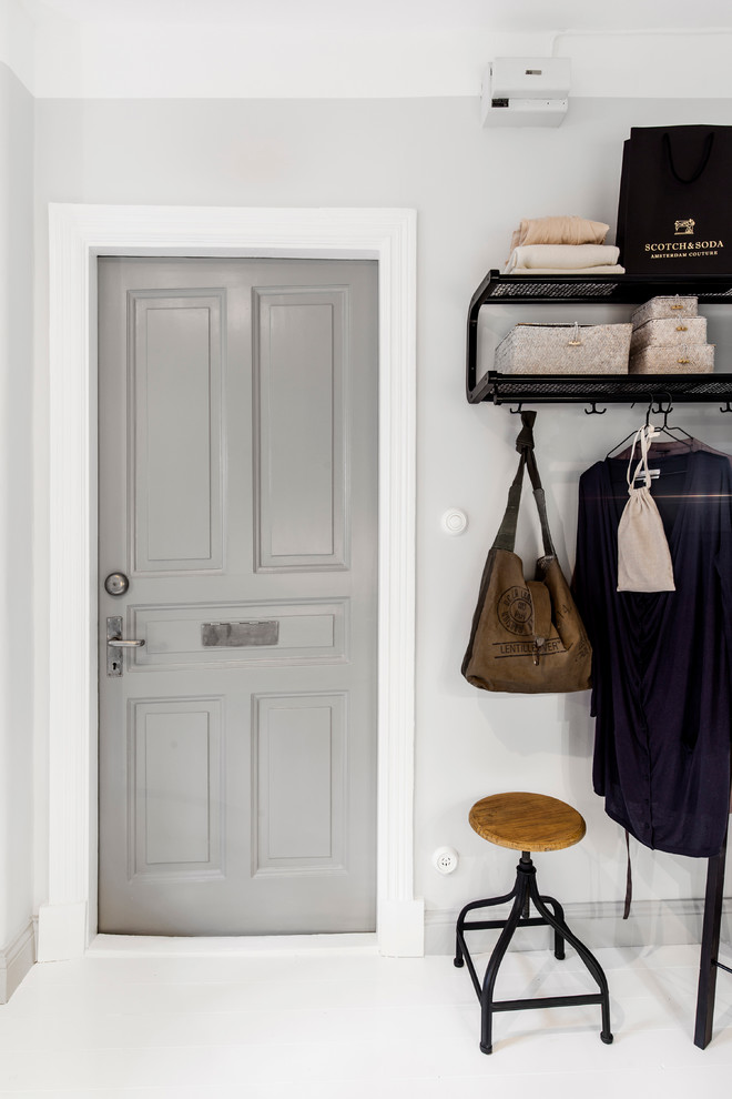 This is an example of a medium sized scandinavian hallway in Gothenburg with white walls, painted wood flooring, a single front door and white floors.