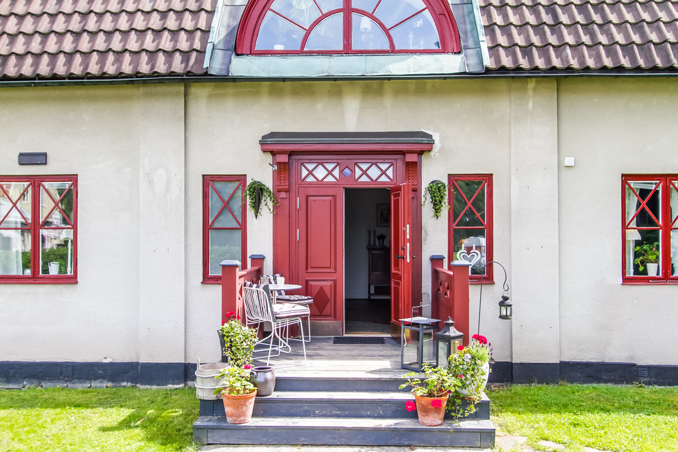 ストックホルムにある高級な広い北欧スタイルのおしゃれな玄関ドア (赤いドア、白い壁、コンクリートの床) の写真