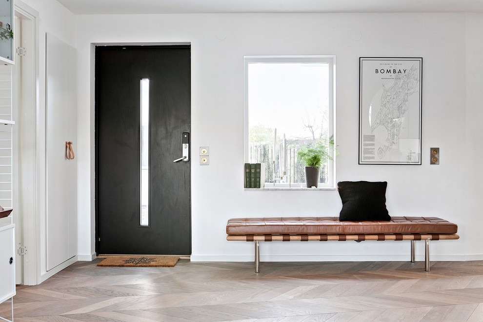 Großer Moderner Eingang mit weißer Wandfarbe, hellem Holzboden, Einzeltür, schwarzer Haustür und beigem Boden in Malmö