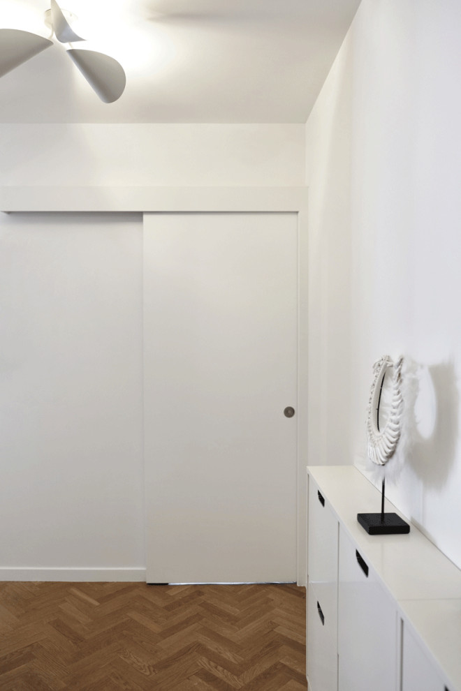 Photo of a medium sized contemporary entrance in Paris with white walls and medium hardwood flooring.