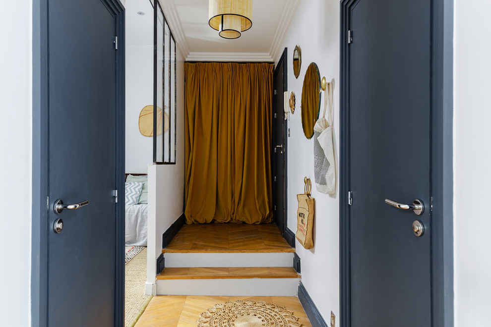 Ejemplo de entrada ecléctica de tamaño medio con paredes blancas, suelo de madera clara y puerta simple