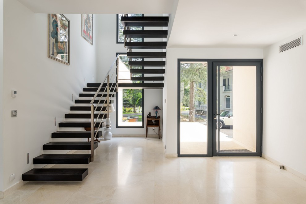 Cette photo montre un grand hall d'entrée tendance avec un mur blanc, un sol en carrelage de céramique, une porte simple et une porte noire.