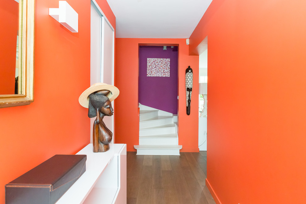 На фото: большое фойе в современном стиле с оранжевыми стенами и темным паркетным полом