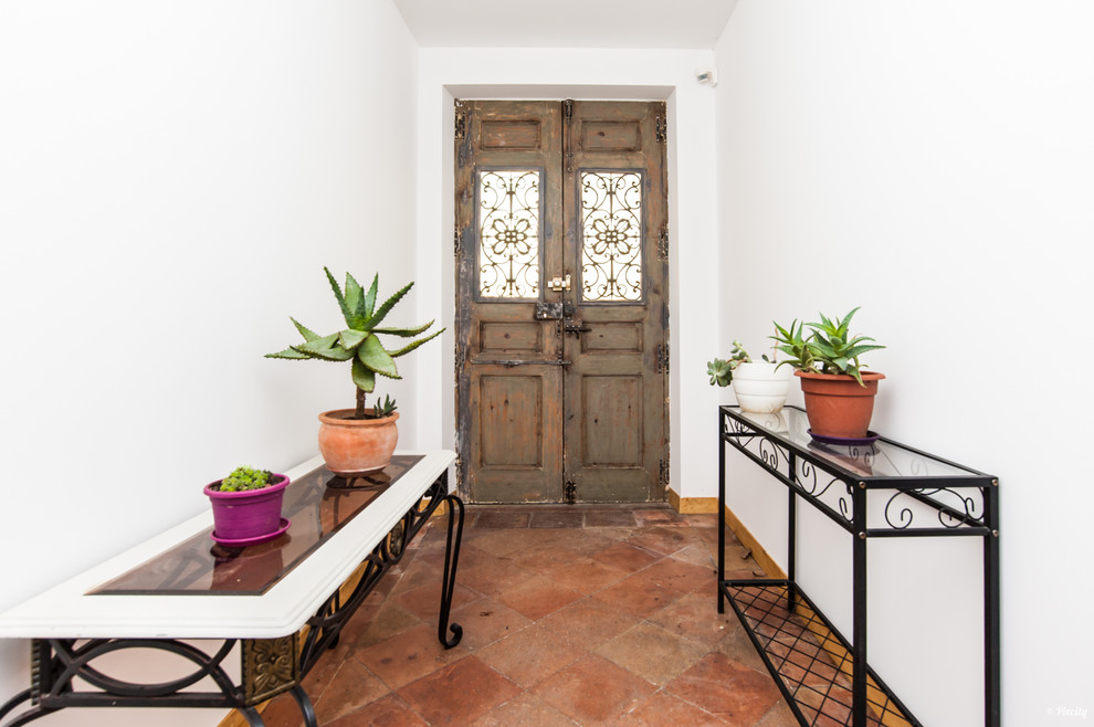 Foto de puerta principal mediterránea con suelo de baldosas de terracota, puerta doble, puerta de madera en tonos medios y suelo rojo
