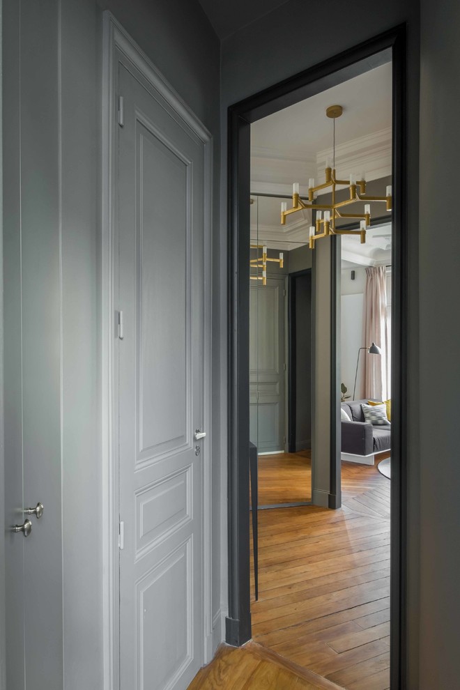 パリにある高級な小さなコンテンポラリースタイルのおしゃれな玄関ロビー (グレーの壁、淡色無垢フローリング、淡色木目調のドア、茶色い床) の写真