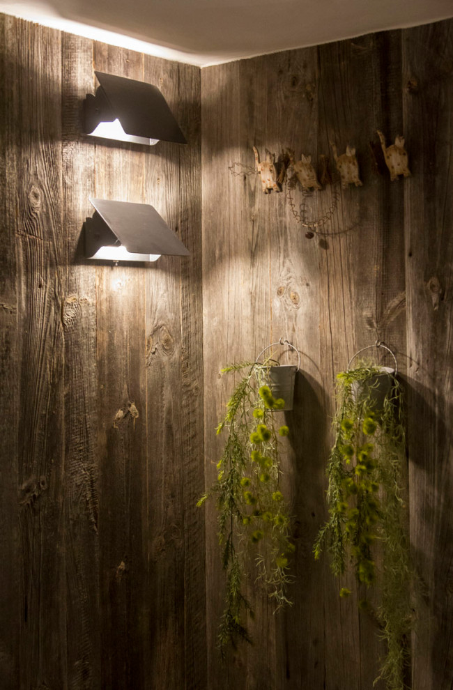 グルノーブルにあるラグジュアリーな中くらいなラスティックスタイルのおしゃれな玄関ラウンジ (ベージュの壁、無垢フローリング、木目調のドア、黒い床) の写真