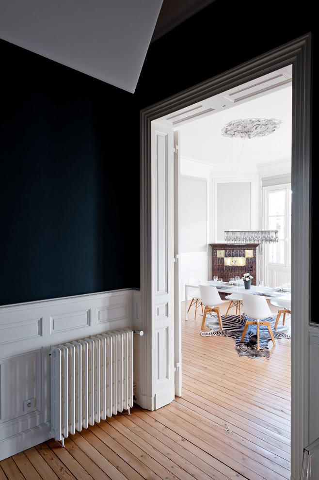 Cette image montre un grand hall d'entrée design avec un mur bleu, parquet clair, une porte simple, une porte blanche et un sol marron.