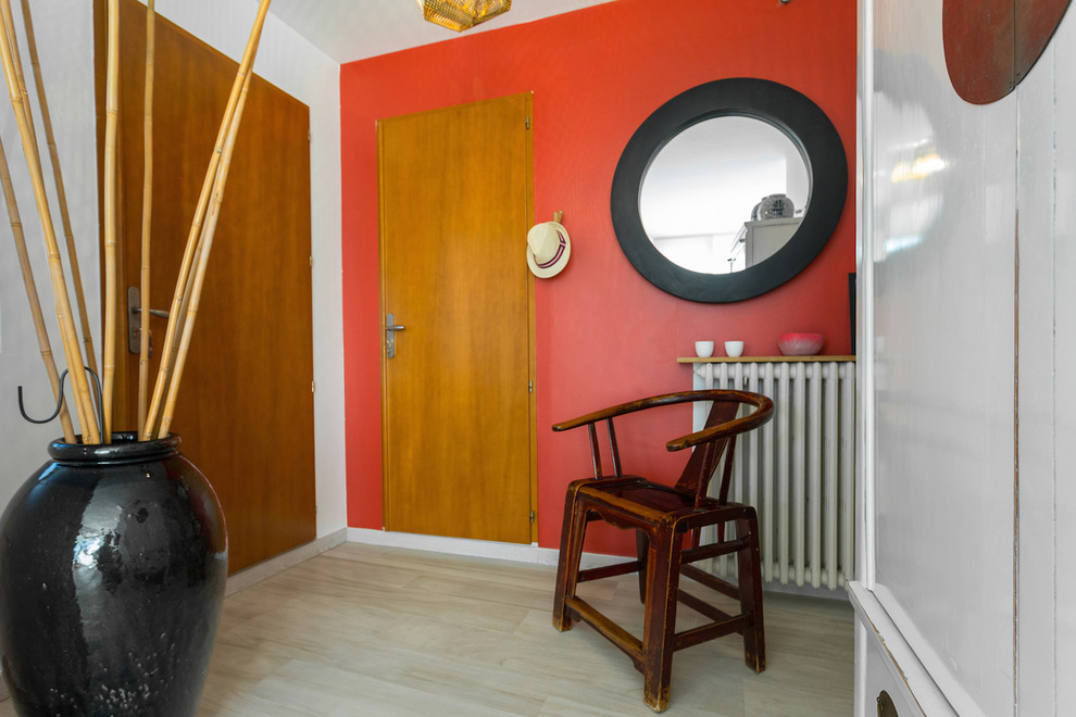 Cette photo montre un vestibule exotique avec un mur rouge, une porte simple, une porte en bois brun et parquet clair.