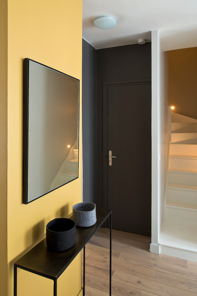 Idées déco pour une porte d'entrée contemporaine avec un mur noir, une porte simple, une porte noire et un sol marron.