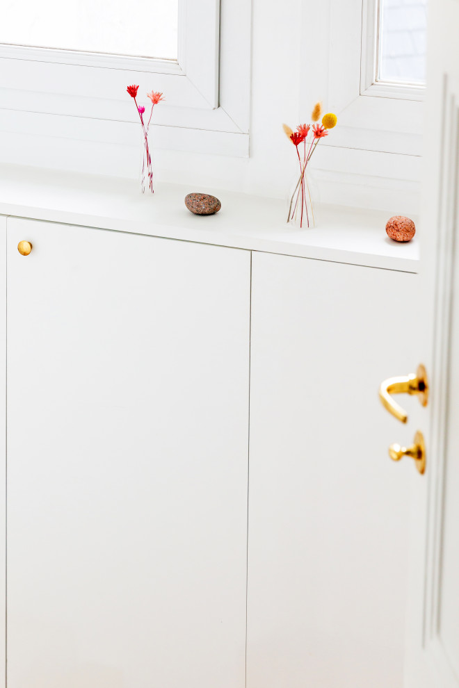 Shabby chic-inspirerad inredning av en liten foajé, med vita väggar, ljust trägolv, en enkeldörr, en vit dörr och brunt golv