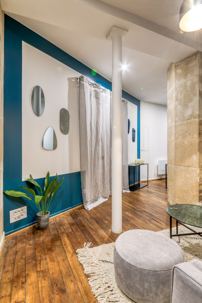 Mittelgroßes Modernes Lesezimmer ohne Kamin mit blauer Wandfarbe, braunem Holzboden, braunem Boden und freistehendem Schreibtisch in Paris