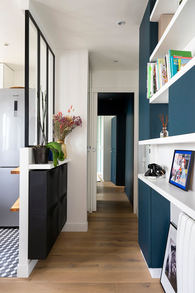 Example of a small medium tone wood floor entry hall design in Paris with blue walls
