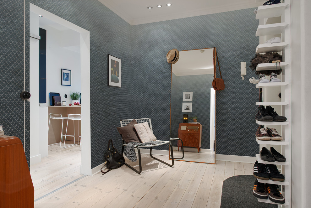 Cette photo montre une entrée tendance de taille moyenne avec un vestiaire, un mur bleu et parquet clair.
