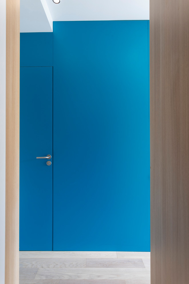 Kleiner Moderner Eingang mit Stauraum, weißer Wandfarbe, hellem Holzboden, Schiebetür, heller Holzhaustür und beigem Boden in Sonstige