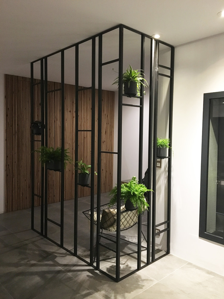 This is an example of a medium sized modern foyer in Toulouse with white walls, ceramic flooring and grey floors.