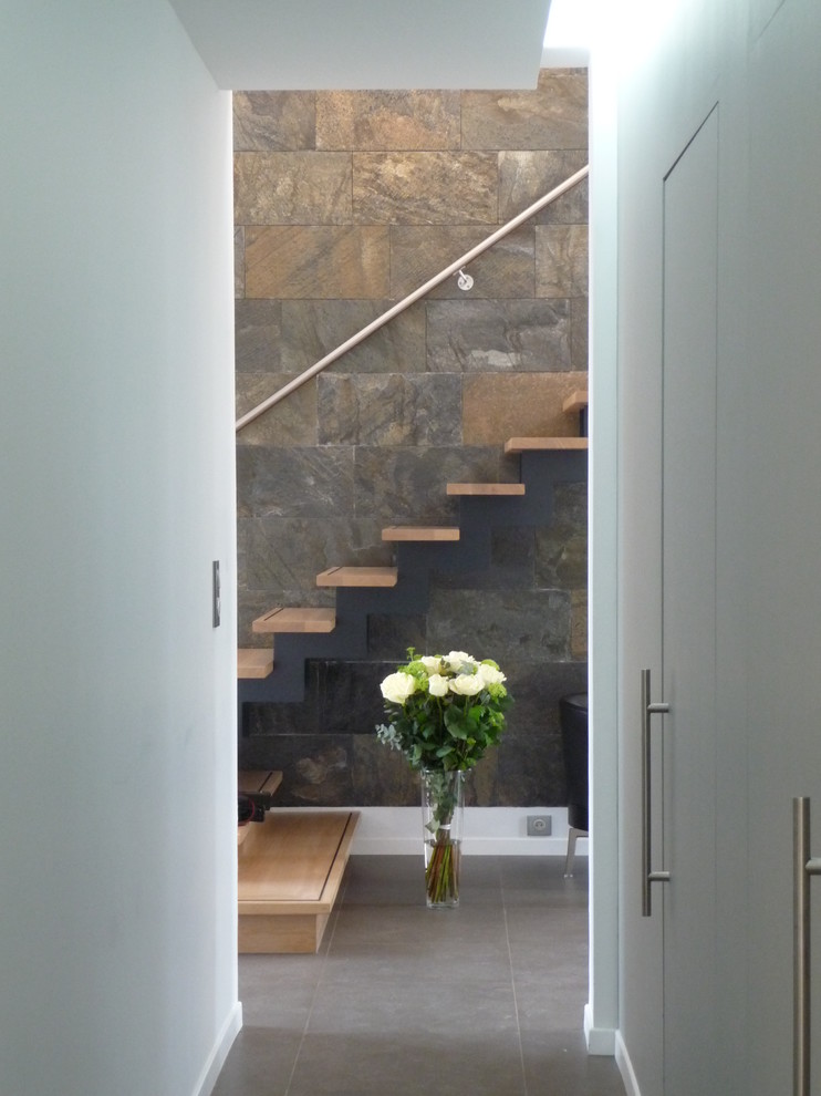 Esempio di un grande corridoio minimal con pareti bianche, pavimento con piastrelle in ceramica e pavimento grigio