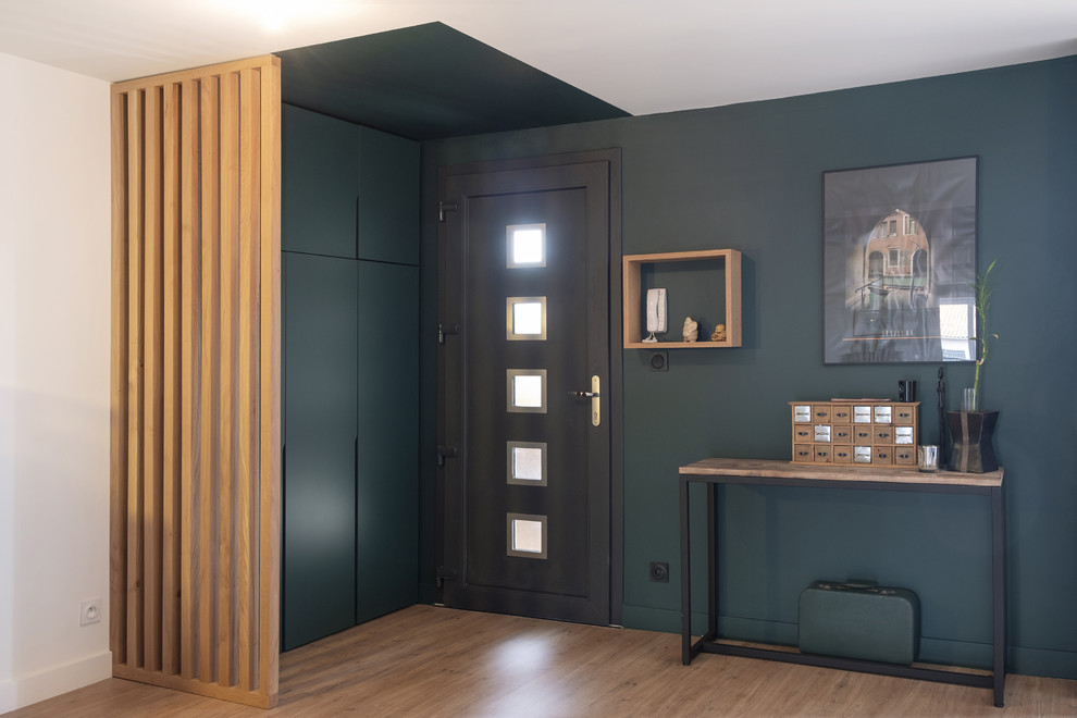 Cette photo montre une entrée tendance de taille moyenne avec un vestiaire, un mur vert, une porte simple et une porte grise.