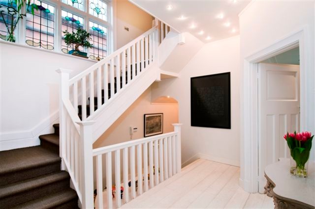 Entryway - large contemporary painted wood floor entryway idea in London with white walls and a white front door