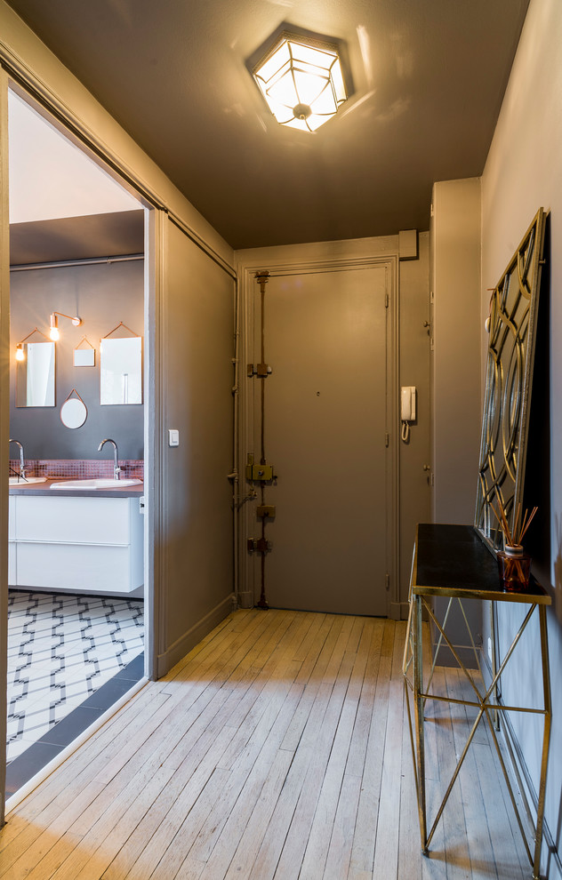 Esempio di un ingresso minimalista di medie dimensioni con pareti grigie, parquet chiaro, una porta singola e pavimento beige