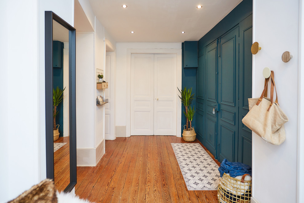 他の地域にあるお手頃価格の巨大なコンテンポラリースタイルのおしゃれな玄関ロビー (白い壁、無垢フローリング、茶色い床、青いドア) の写真