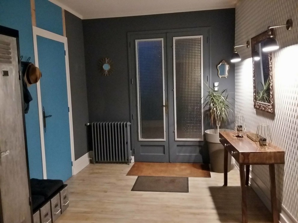 60 tals inredning av en mellanstor foajé, med blå väggar, ljust trägolv, en dubbeldörr, en grå dörr och beiget golv