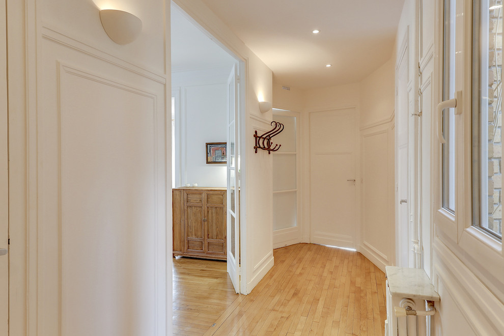Foto di un piccolo corridoio eclettico con parquet chiaro, pareti beige, una porta singola e una porta bianca