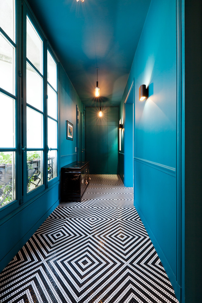 パリにあるお手頃価格の中くらいなエクレクティックスタイルのおしゃれな玄関ホール (青い壁、黒い床、セラミックタイルの床、青いドア) の写真
