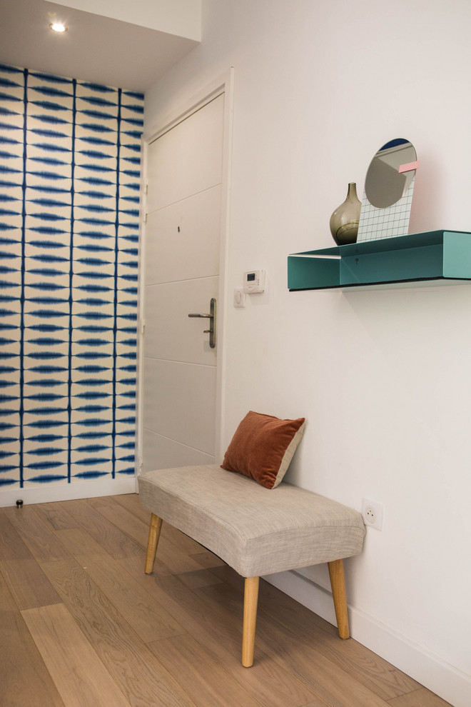Foto di un ingresso minimalista con pareti blu, pavimento in legno massello medio e una porta bianca