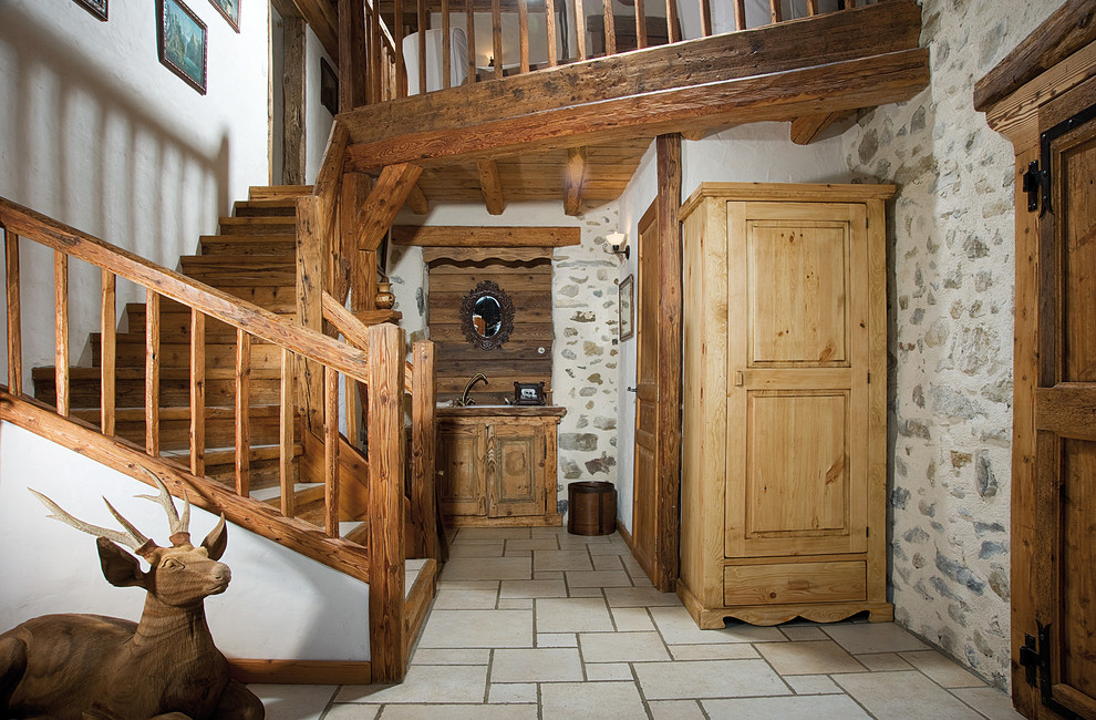 Cette image montre un hall d'entrée chalet de taille moyenne avec un mur blanc et une porte en bois brun.