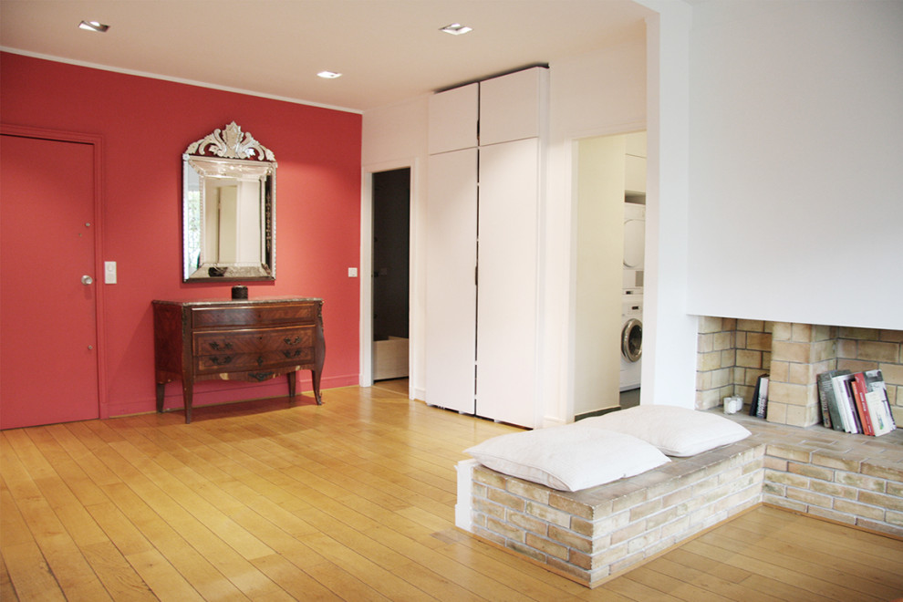 お手頃価格の広いコンテンポラリースタイルのおしゃれな玄関ロビー (赤い壁、淡色無垢フローリング、赤いドア、茶色い床) の写真