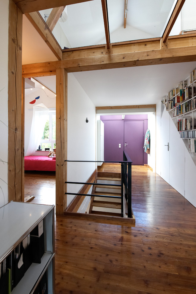Ispirazione per un ampio ingresso minimal con pareti bianche, pavimento in legno massello medio e una porta viola