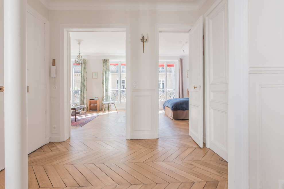パリにある高級な広いトラディショナルスタイルのおしゃれな玄関ロビー (白い壁、無垢フローリング、白いドア、ベージュの床) の写真