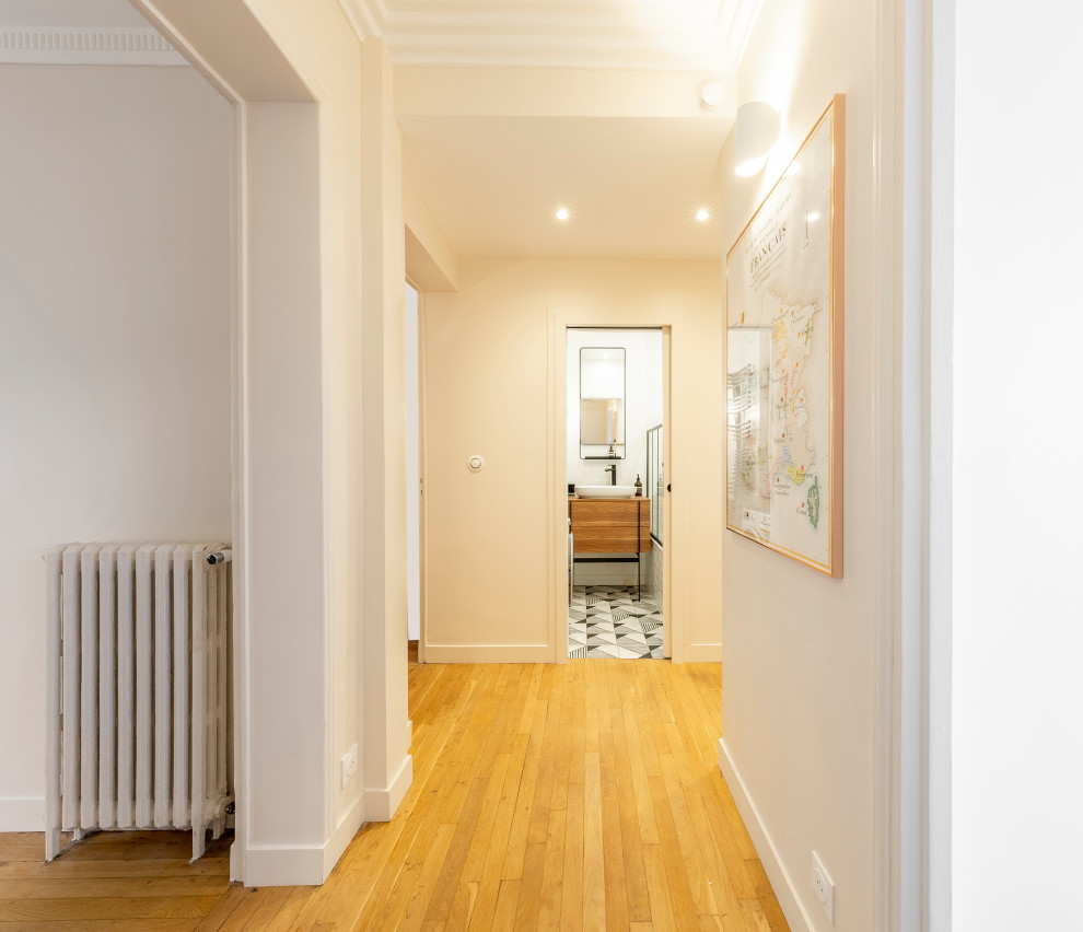 Modelo de hall contemporáneo pequeño con paredes beige, suelo de madera clara, puerta doble y puerta blanca