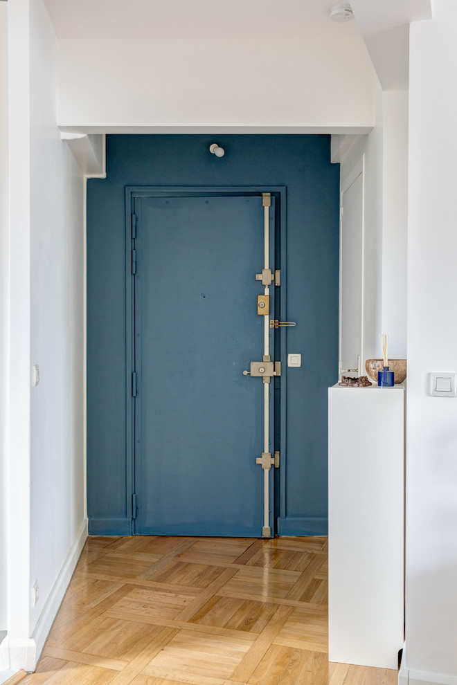 パリにあるお手頃価格の中くらいな北欧スタイルのおしゃれな玄関ロビー (白い壁、無垢フローリング、青いドア、ベージュの床) の写真
