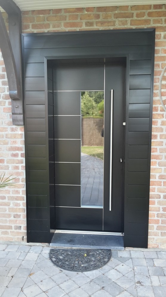 Medium sized modern front door in Lille with orange walls and a grey front door.