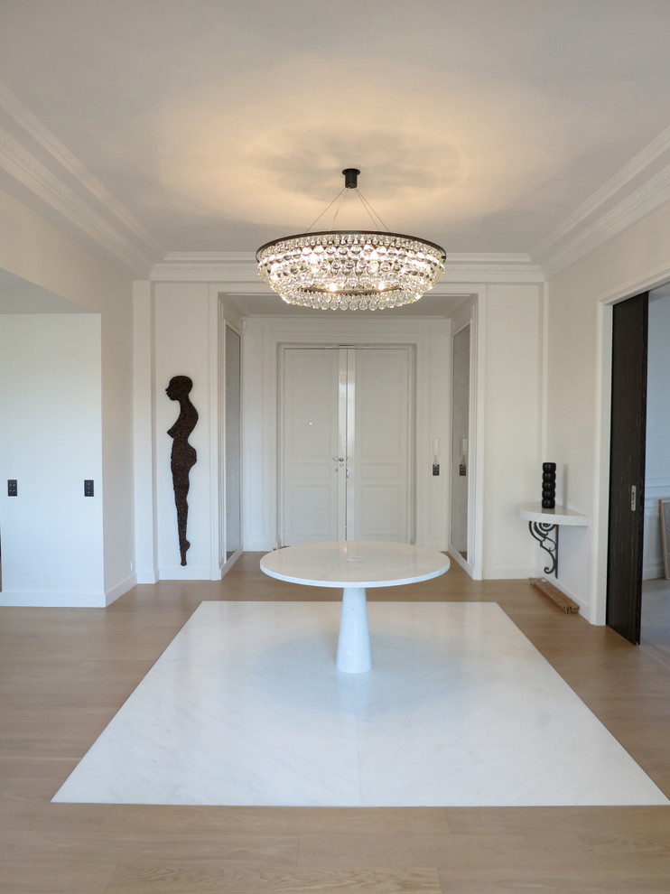 Cette image montre un grand hall d'entrée design avec un mur blanc et un sol en bois brun.