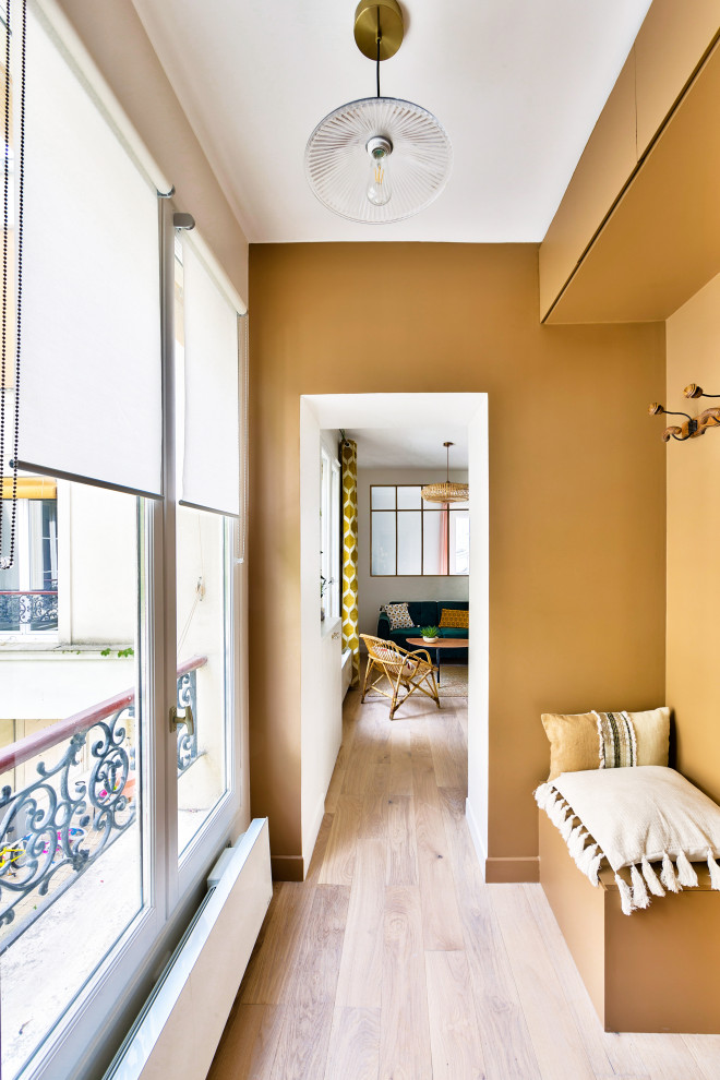 パリにある高級な中くらいなトランジショナルスタイルのおしゃれな玄関ラウンジ (茶色い壁、淡色無垢フローリング、茶色いドア) の写真