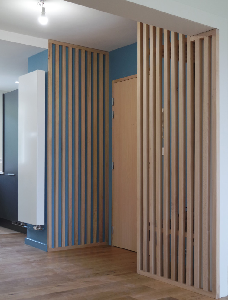 Skandinavischer Eingang mit Stauraum, blauer Wandfarbe, braunem Holzboden, Einzeltür und heller Holzhaustür in Sonstige