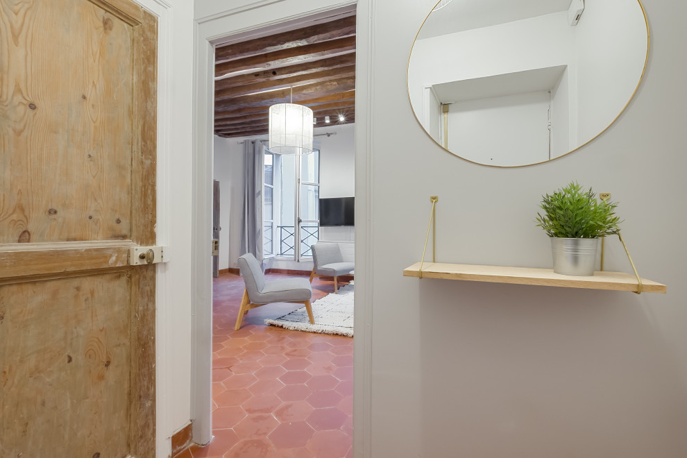 This is an example of a scandinavian entrance in Paris with grey walls, terracotta flooring and red floors.