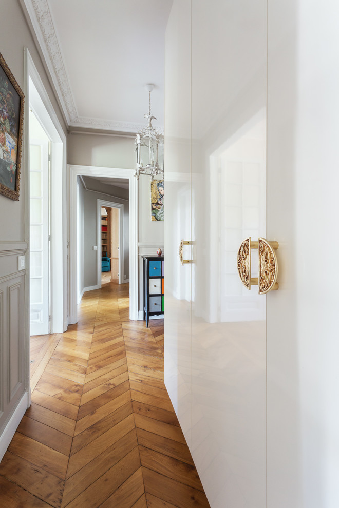 Example of a mid-sized trendy medium tone wood floor and brown floor foyer design in Paris with beige walls