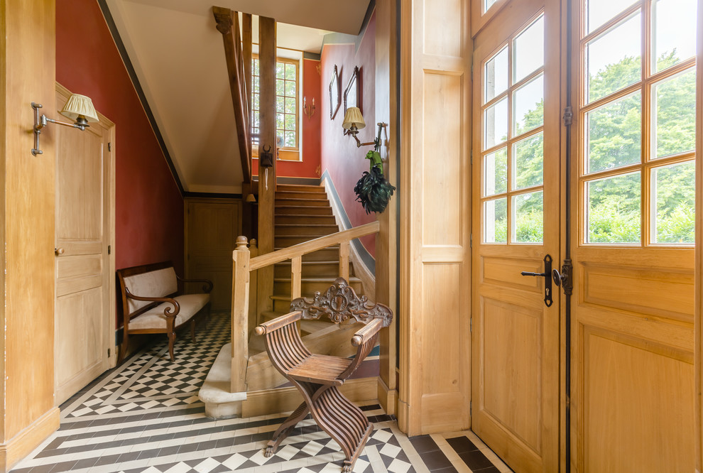 Klassisches Foyer mit roter Wandfarbe, Doppeltür, Haustür aus Glas und buntem Boden in Paris