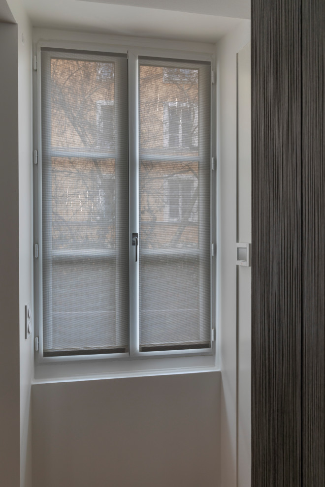 Modern inredning av en liten foajé, med vita väggar, ljust trägolv, en enkeldörr, en vit dörr och beiget golv