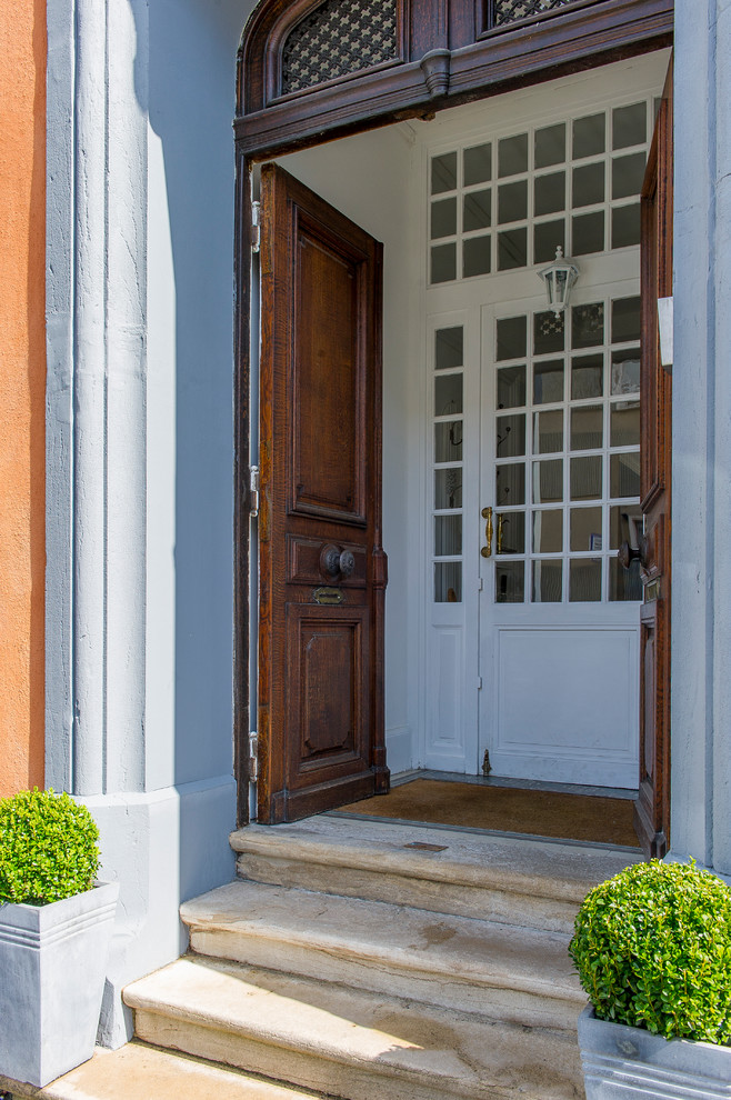 Réalisation d'une porte d'entrée tradition avec un mur gris, une porte double et une porte en bois foncé.