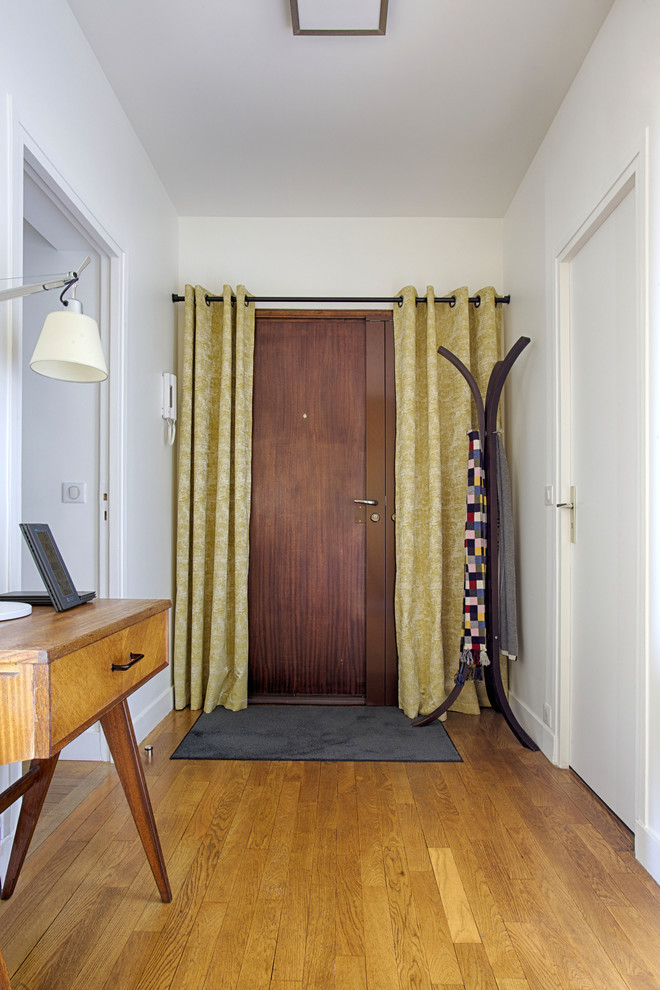 他の地域にある低価格の広いモダンスタイルのおしゃれな玄関ロビー (白い壁、淡色無垢フローリング、木目調のドア、ベージュの床) の写真