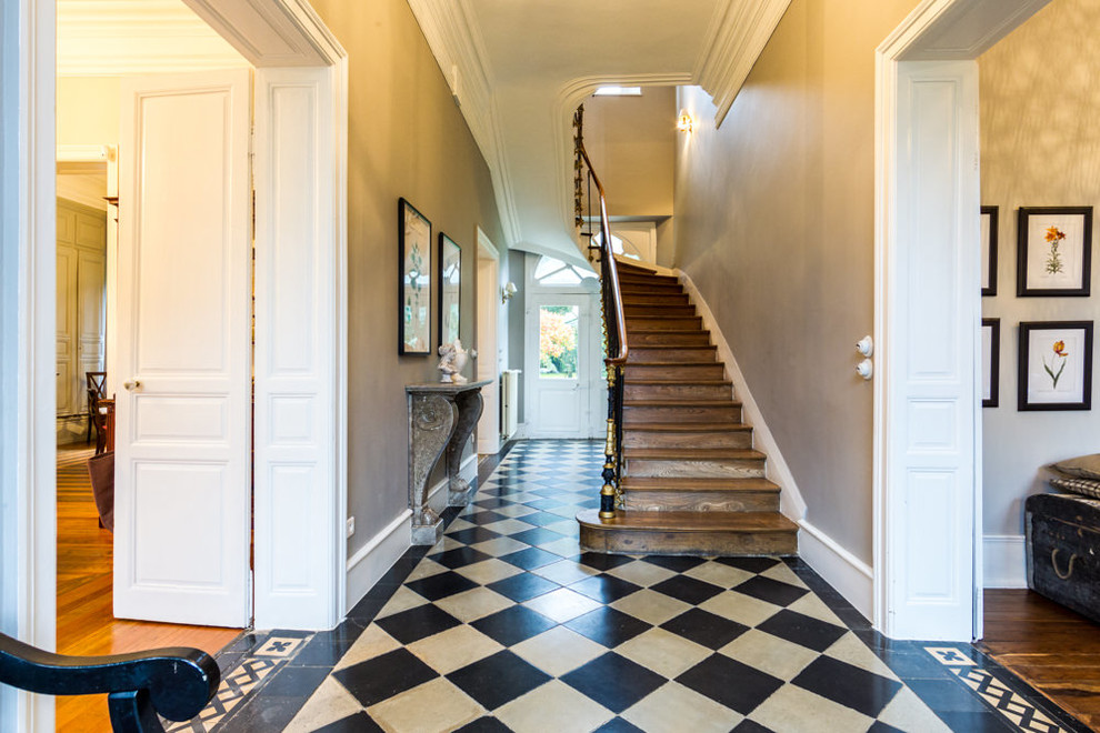 Immagine di un corridoio classico con pareti beige, pavimento multicolore, una porta a due ante e una porta bianca