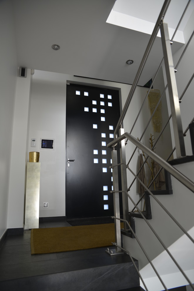 Idee per una piccola porta d'ingresso minimal con pareti bianche, pavimento in ardesia, una porta a pivot e una porta nera