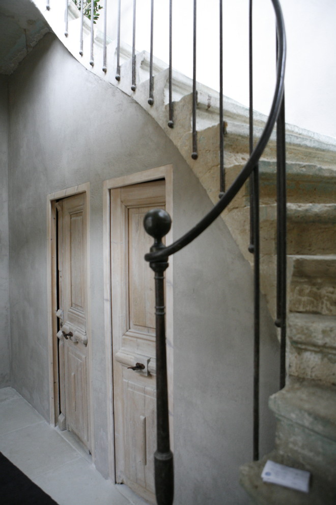 Modelo de entrada industrial con paredes grises, suelo de piedra caliza y puerta de madera clara