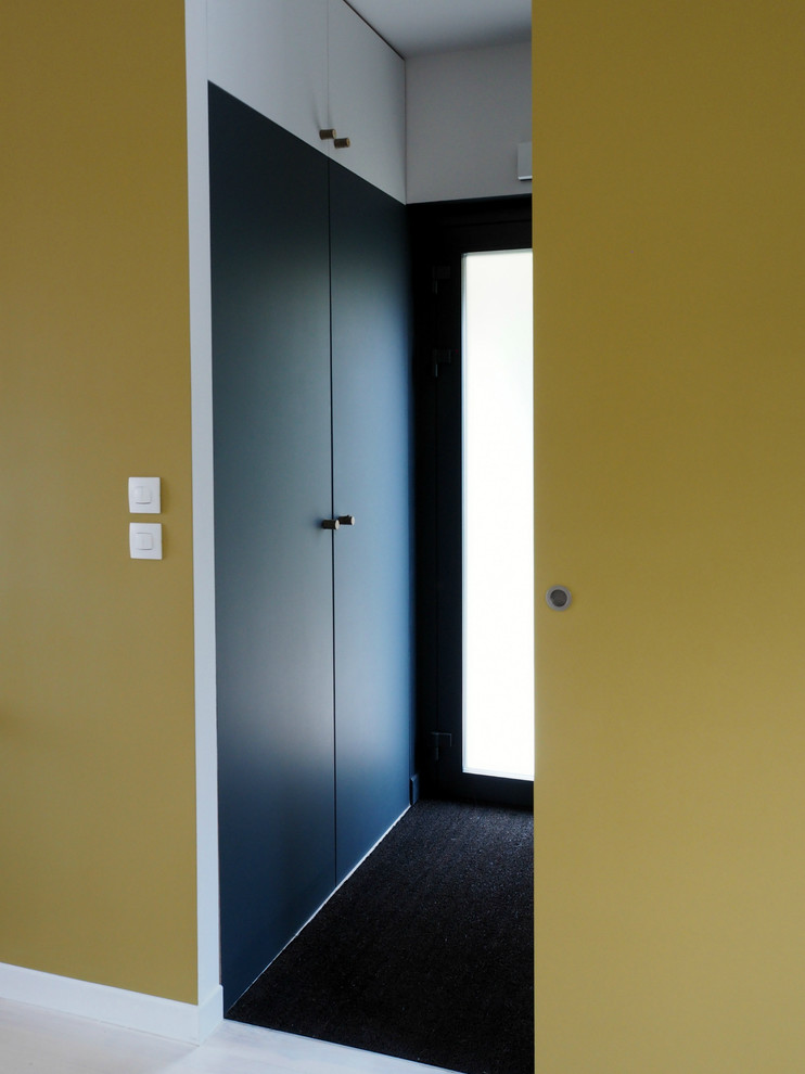 Exemple d'une entrée tendance avec un mur bleu, une porte simple et une porte en verre.